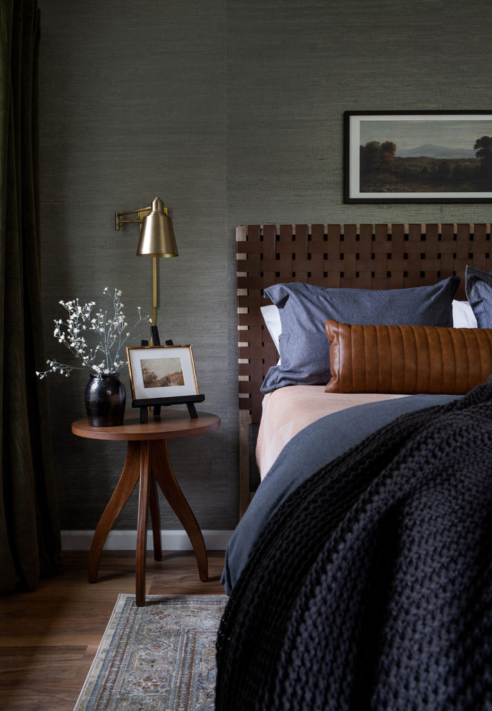 Dark and Moody Bedroom with a woven leather headboard and dark grasscloth walls