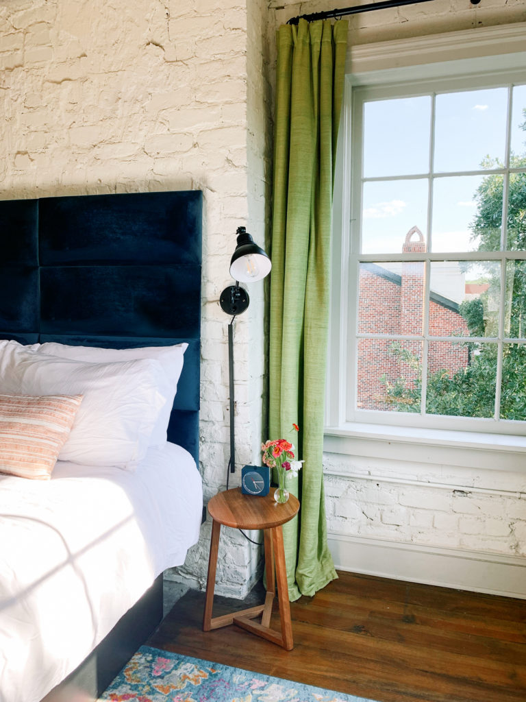 Light and Airy Small Bedroom with a King Bed Decorated with White painted Brick walls and Natural Light Pouring In