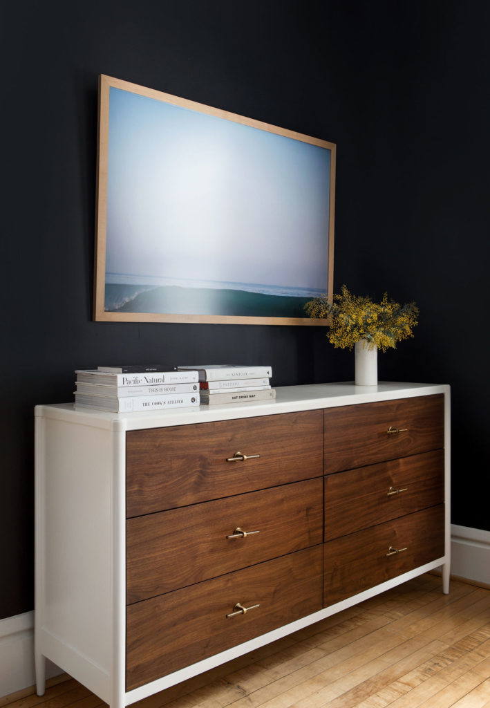 Dark and Moody Small Bedroom with a Kind Sized Bed Decorated with Focal Wall Art and a Wooden Dresser