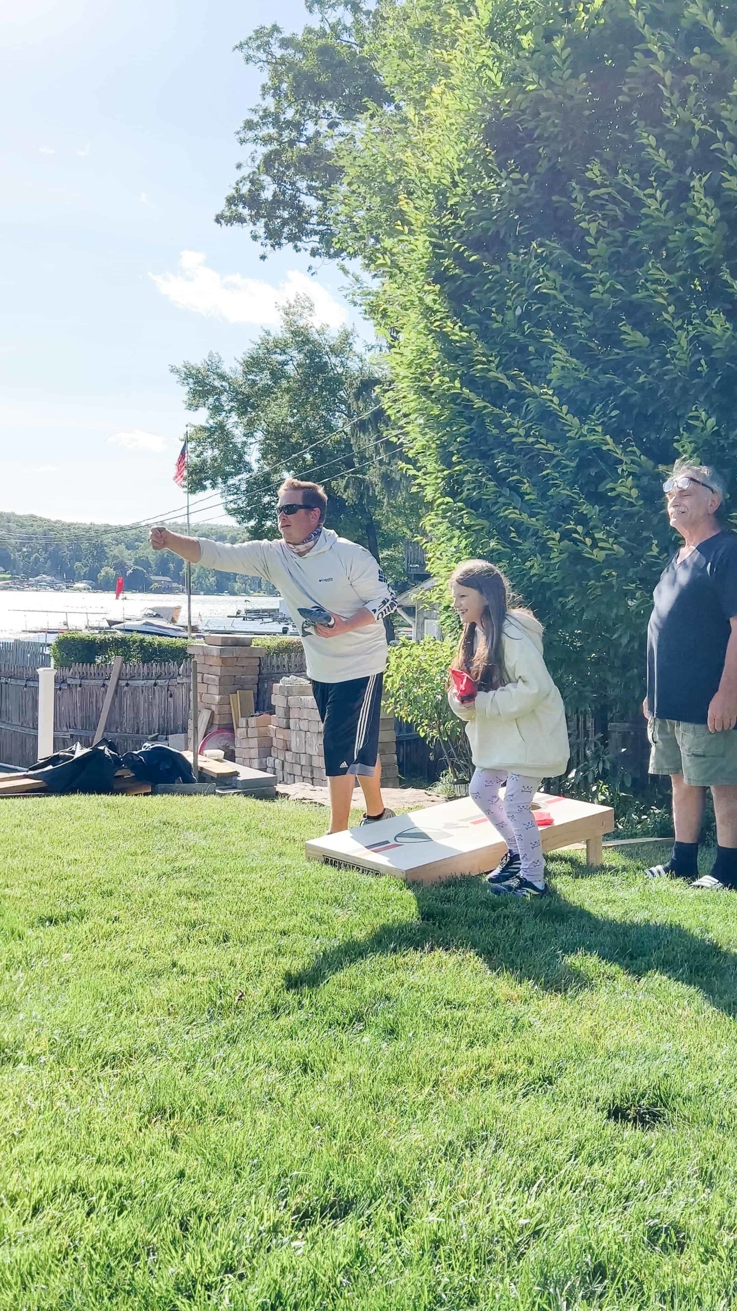Multi-generational family engaged in a friendly game of Cornhole in a lush summer backyard, epitomizing joyful family bonding over outdoor games.